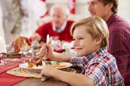 Son With Father And Grandparents Enjoying Christmas Meal